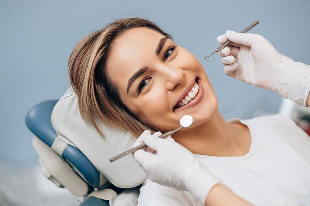 Person holding a chipped tooth fragment in a small container beside gauze and a cold compress.